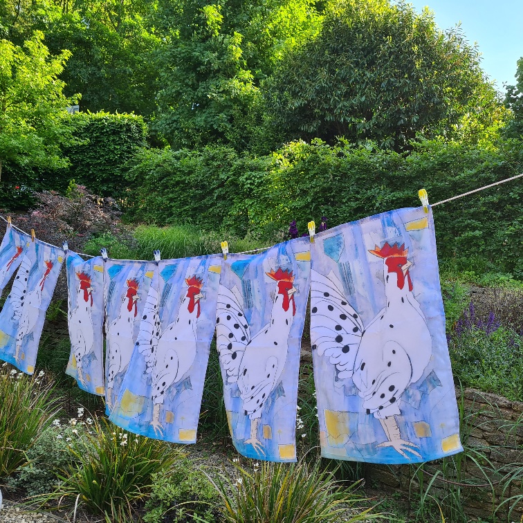 A line of bold rooster tea towels on a washing line
